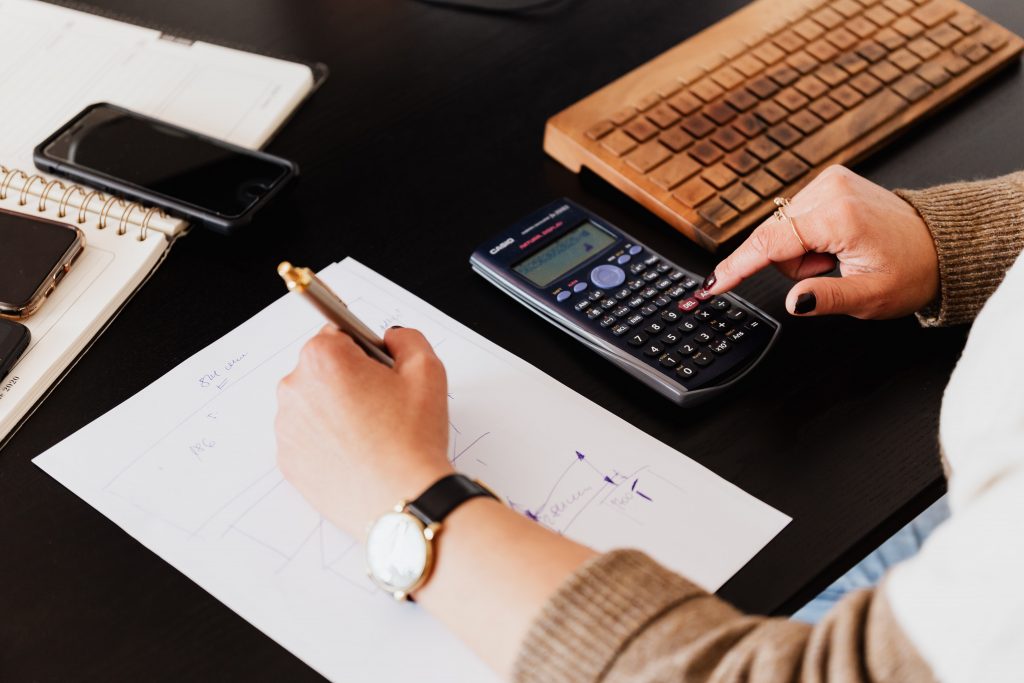 Female DfT Finance professional sitting at computer desk with calculator.
