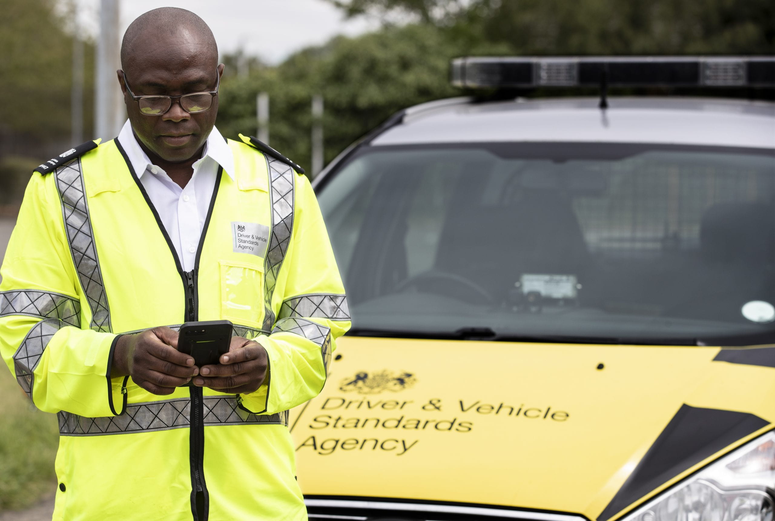 DVSA member of staff standing in front of a DVSA car.