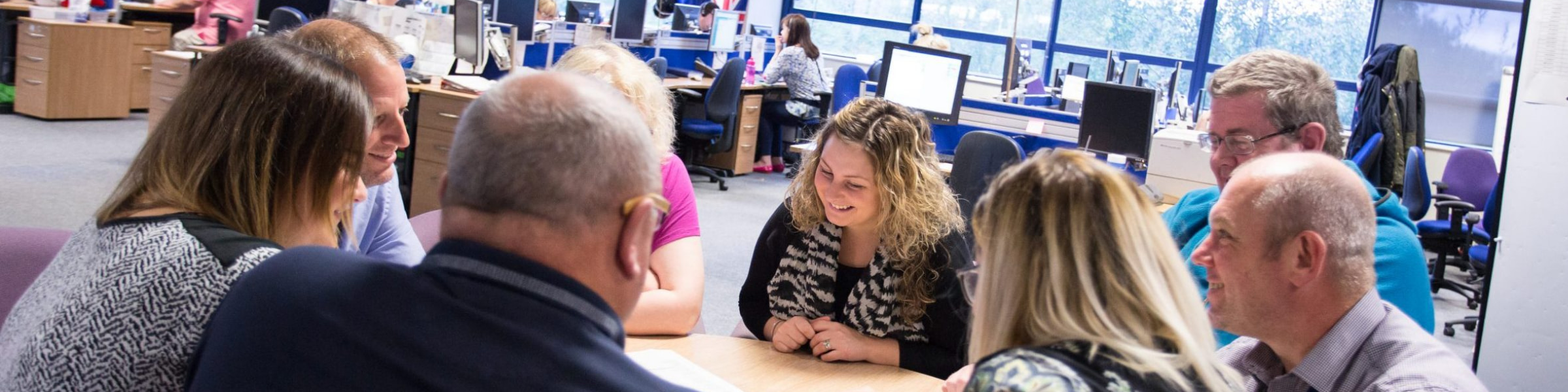 DfT Operational Delivery team gathered around a table and talking.