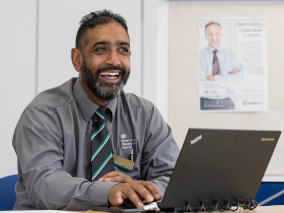 Image of a man working at a laptop in DVSA Driving Examiner uniform.
